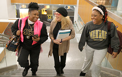 2 students walking up stairs with their professor in the middle.