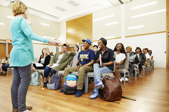 Woman speaking before a group of diverse students in a lecture hall