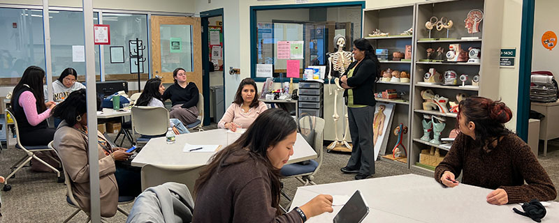 A group of students sitting in tables listening to a presenter