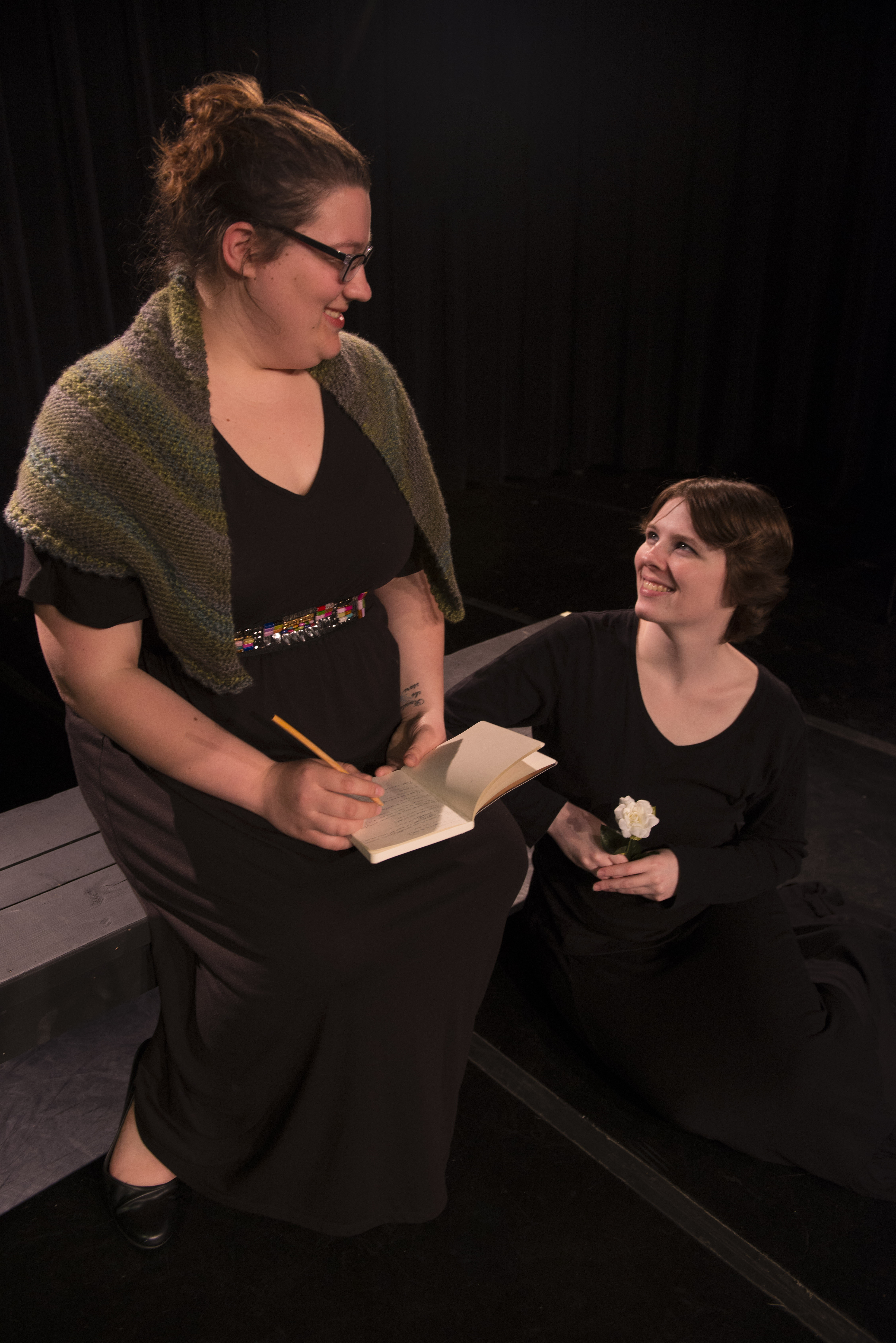 Two female actors sitting down wearing black