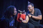 Two theater students in black shirts, one is flexing his bicep
