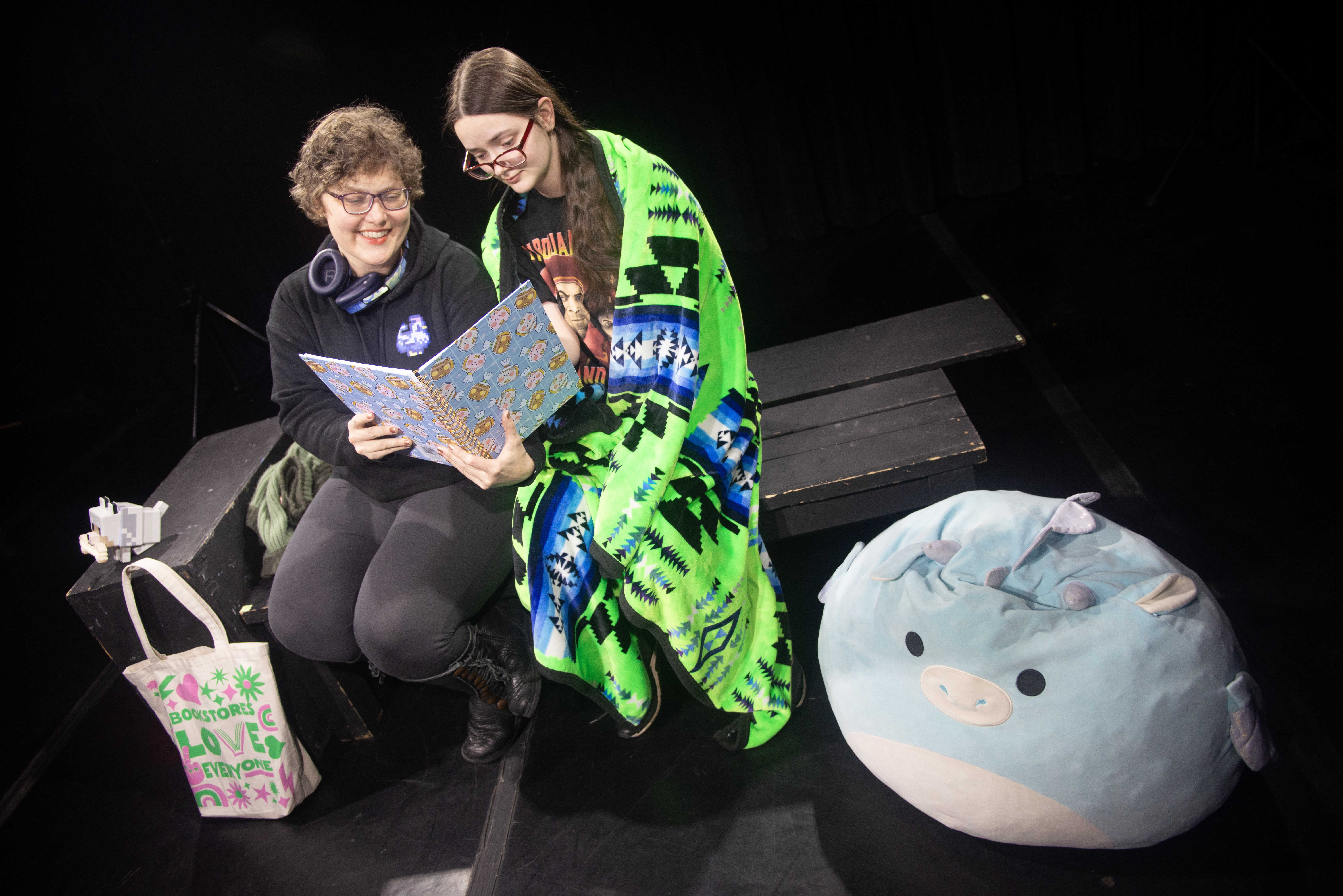 Two women sitting on a bench looking at a book