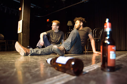 Two actors sitting on the floor with beer bottles