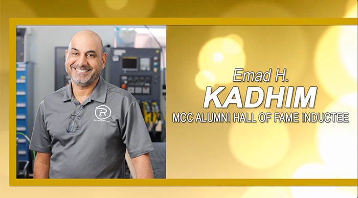 A person smiling in front of machinery, wearing a gray shirt with a logo. The text says "Emad H. Kadhim, MCC Alumni Hall of Fame Inductee" on a golden background.
