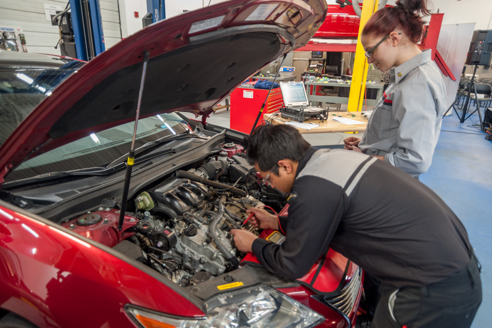 automotive students looking at the engine of a car
