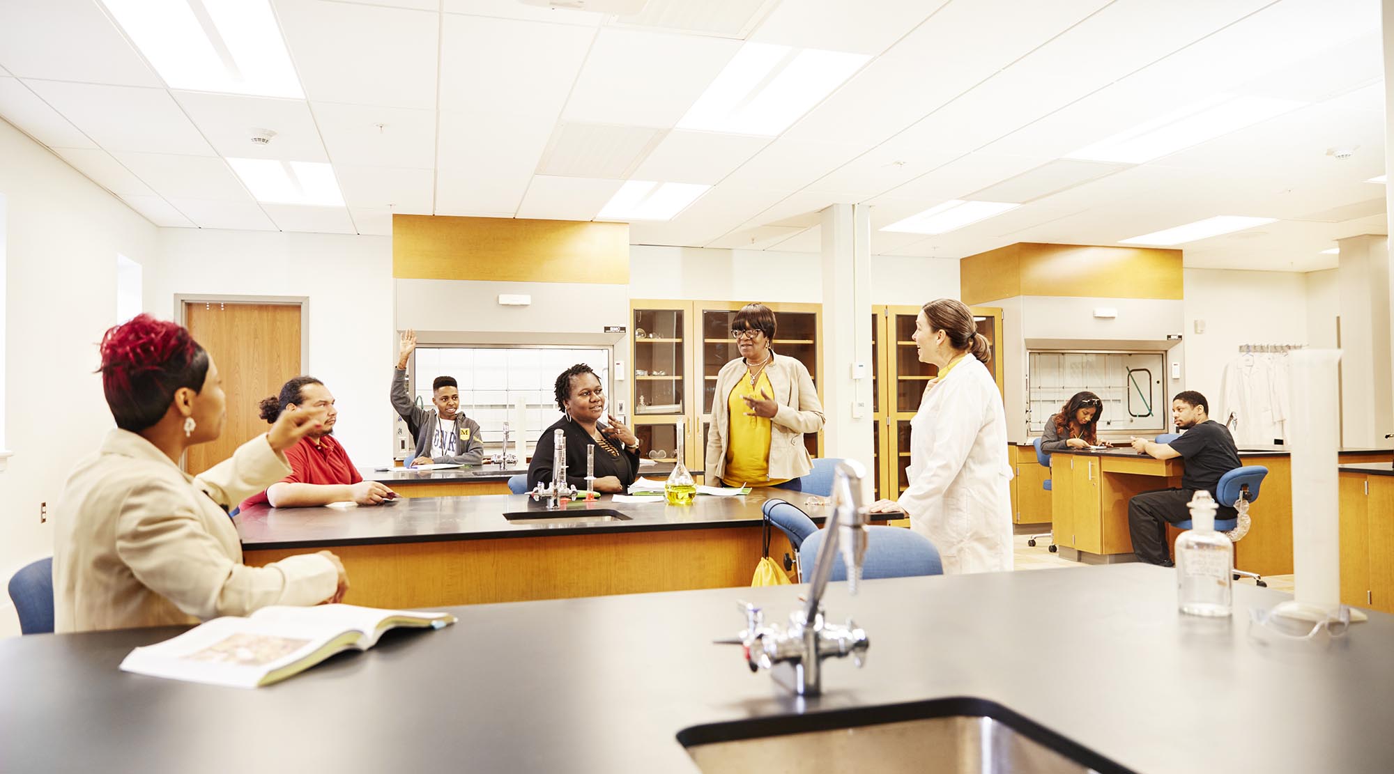 a group of students listening to a professor in a lab