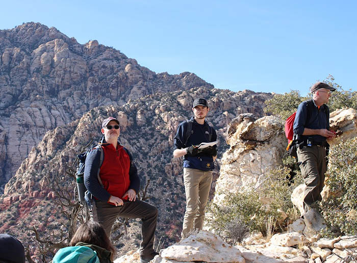 3 people standing on a mountain