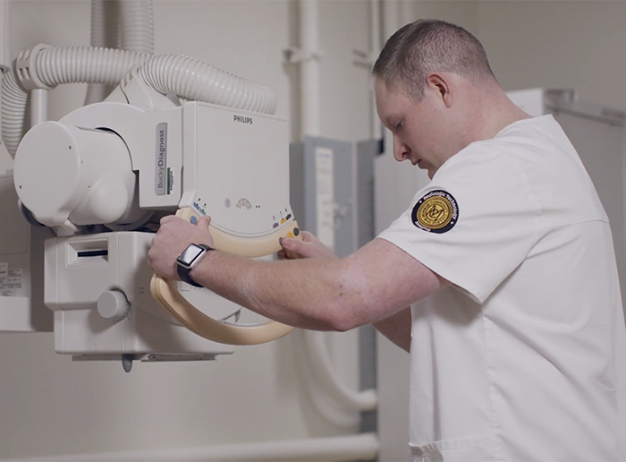Radiologic technology student adjusts an X-ray machine during hands-on clinical training in a medical imaging lab.