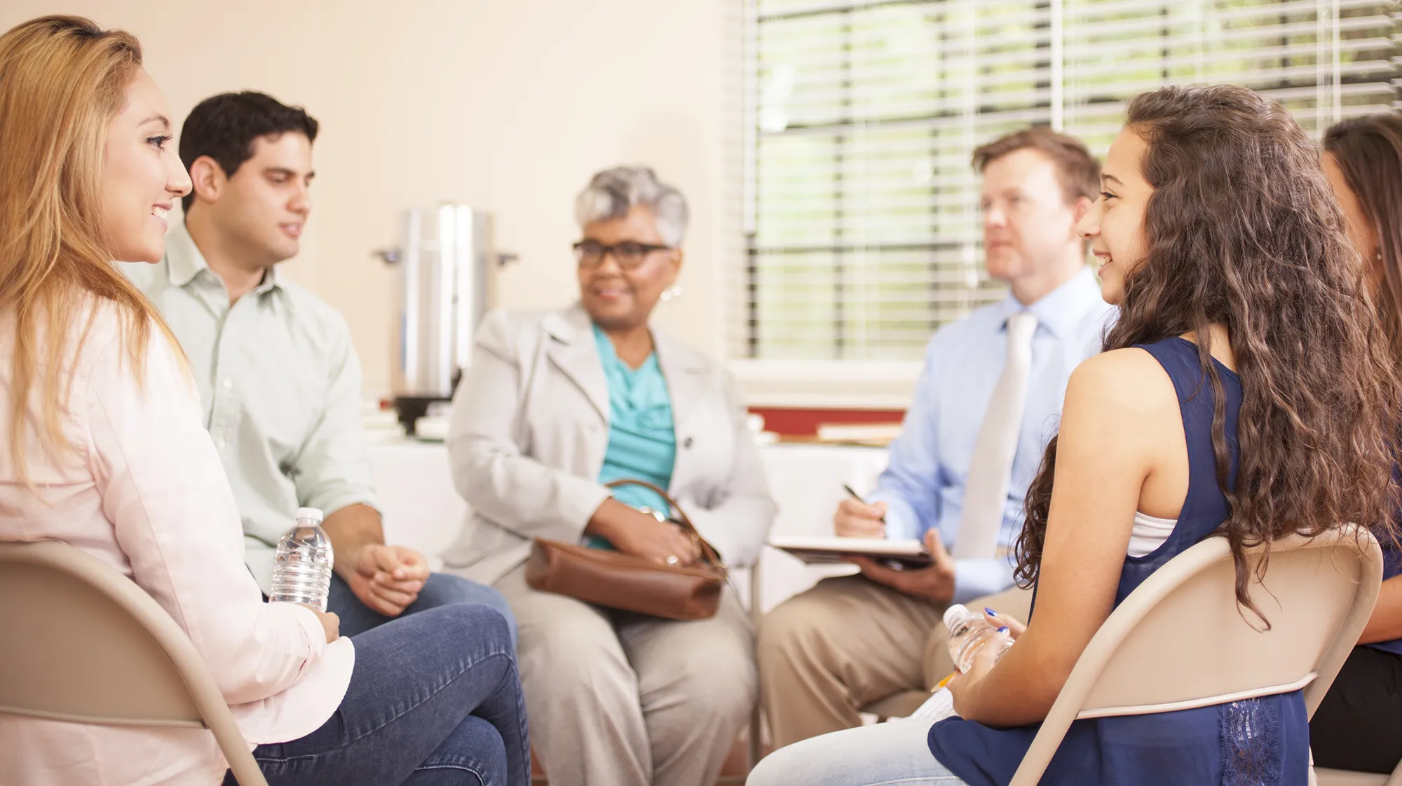 A group of people sits in a circle with a care coordinator
