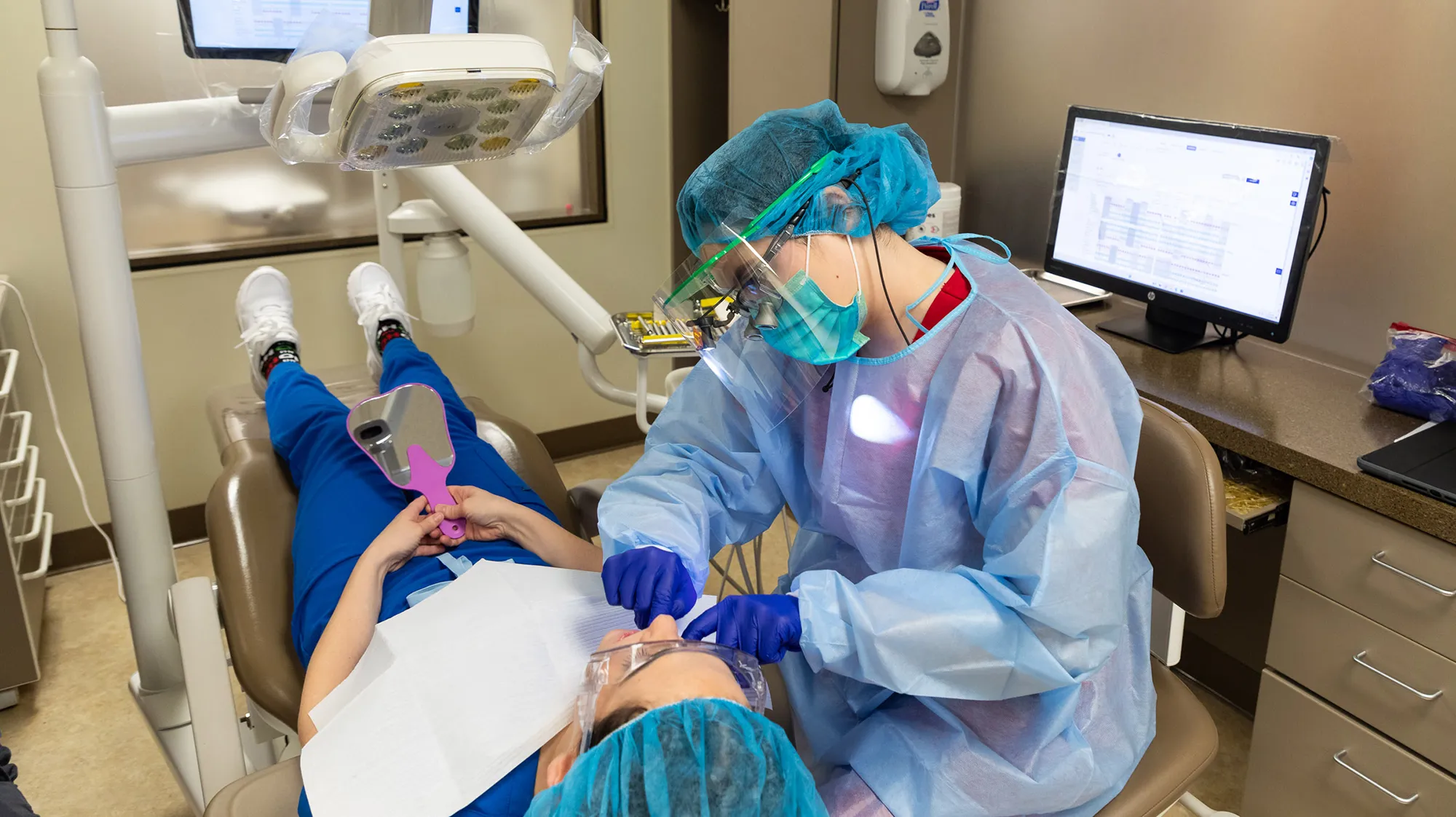 a dental hygiene student cleans the teeth of a patient