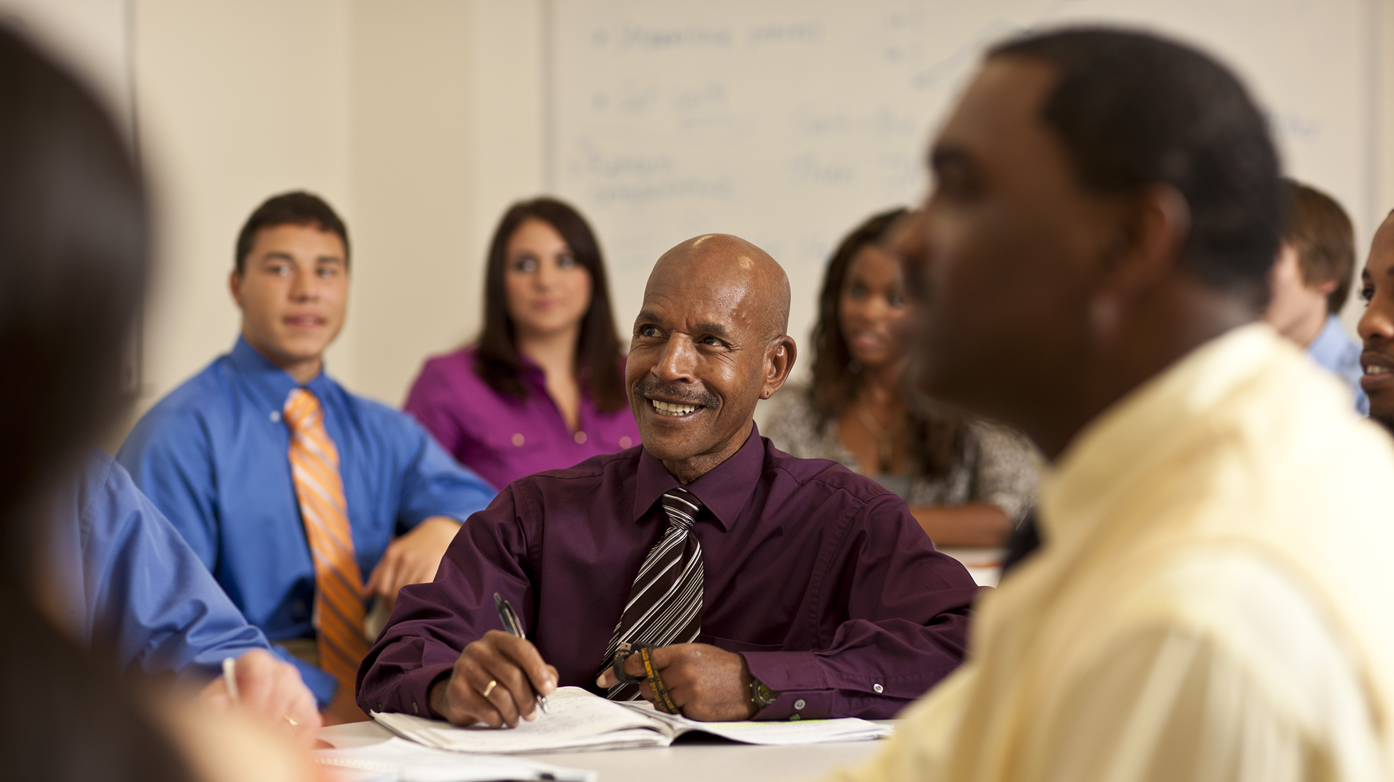 a man smiling in the middle of a class lecture