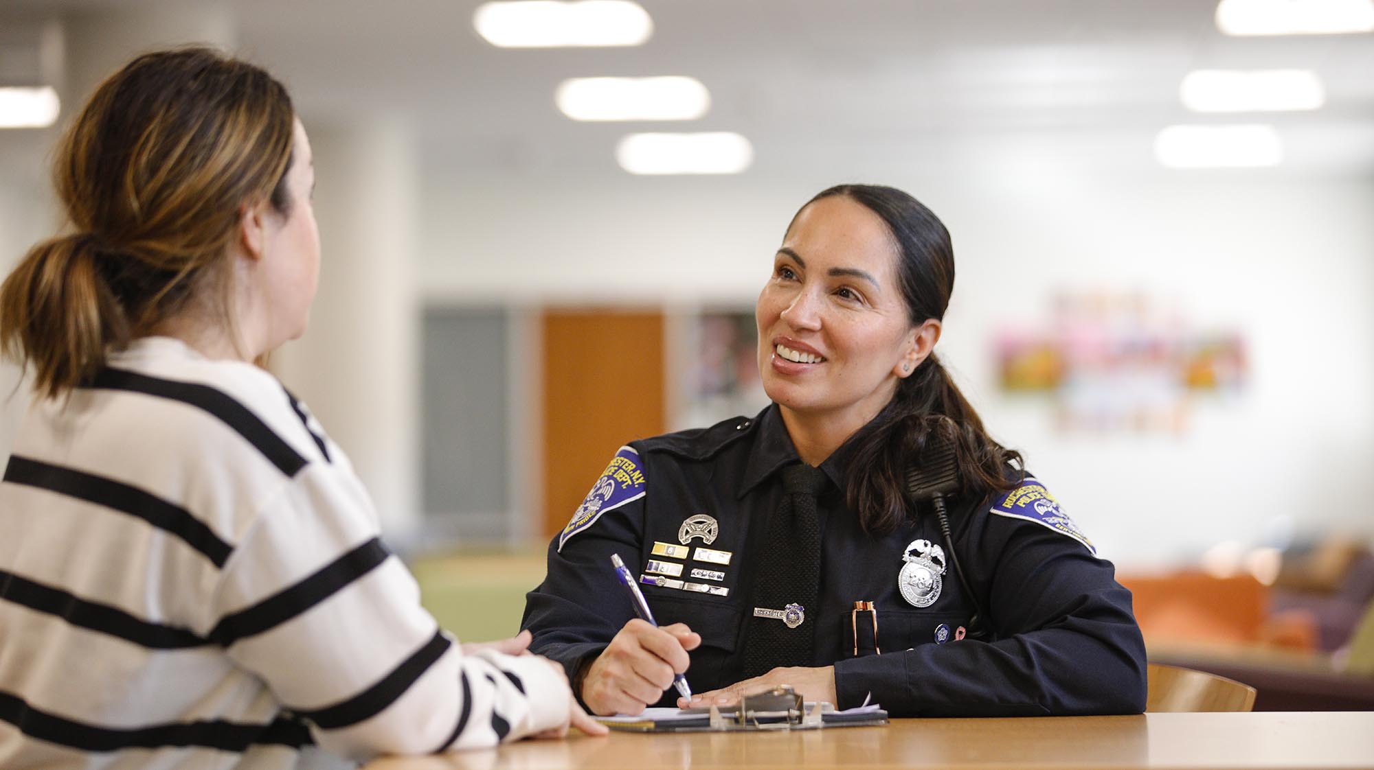 A police officer talks to a woman while taking notes