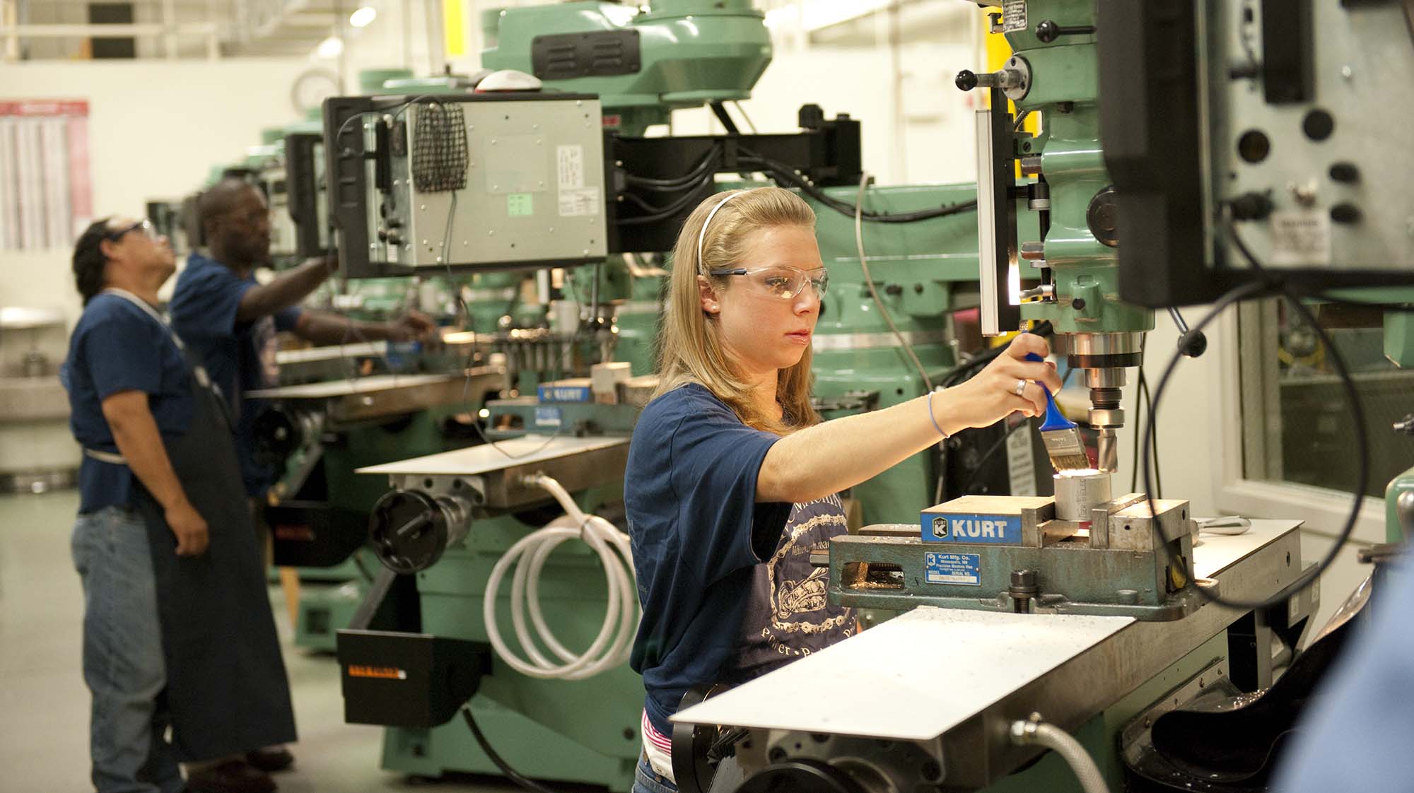 Student operates a precision milling machine while wearing safety glasses in an advanced manufacturing lab.