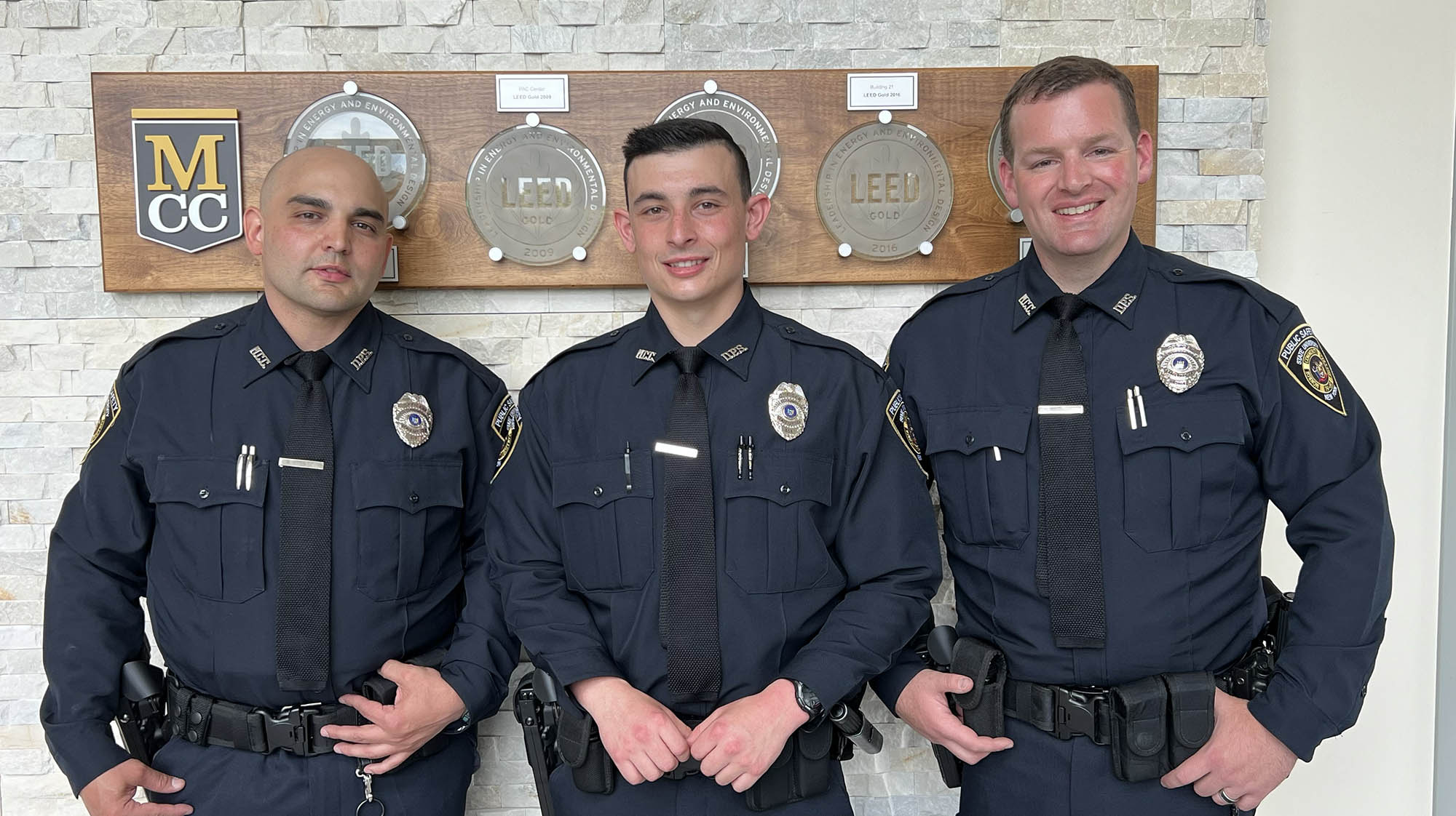 3 public safety officers smiling in uniform