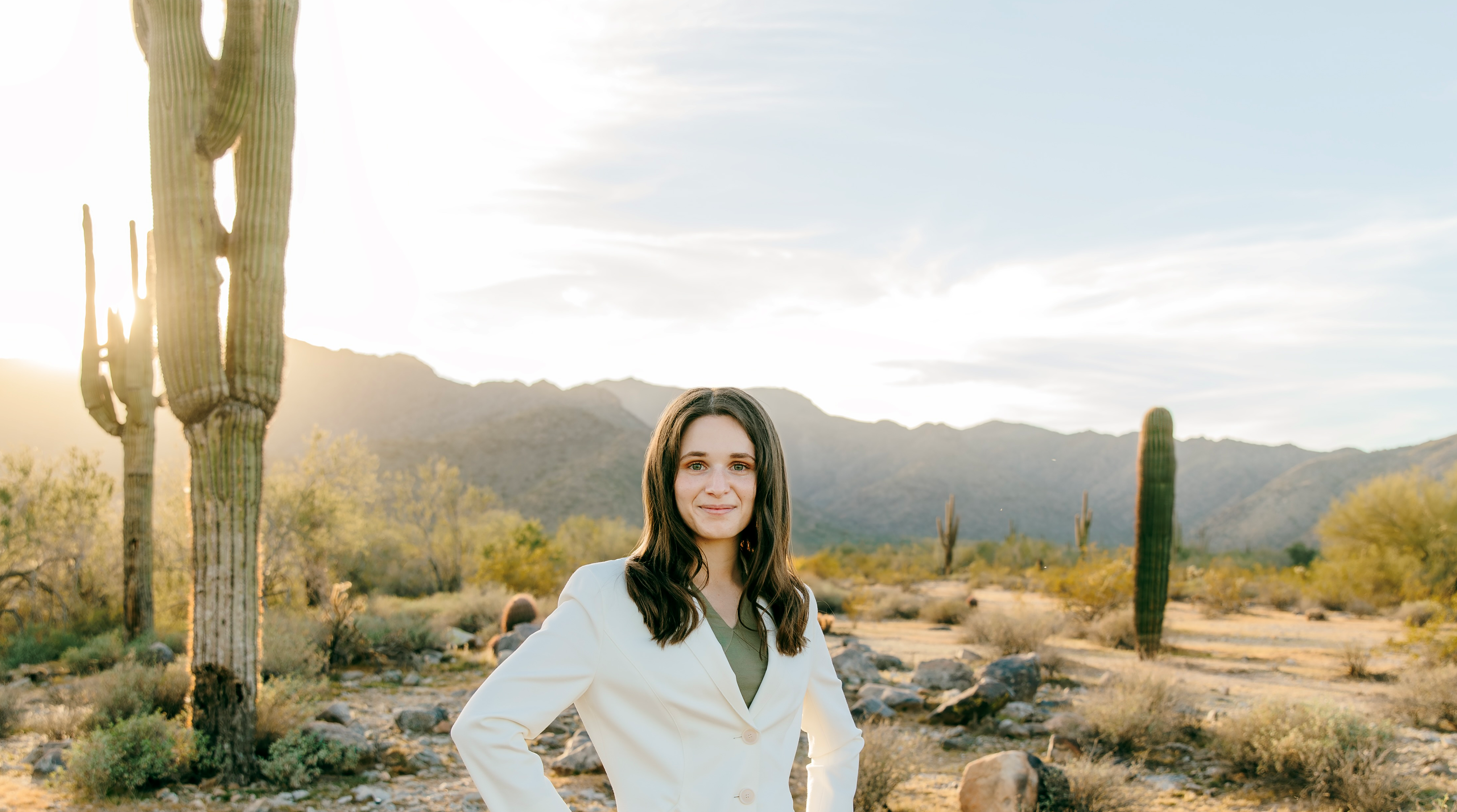 A woman standing in the middle of a dessert with cacti around her