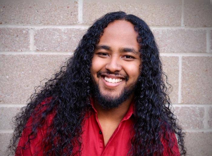 a person with long curly hair smiling