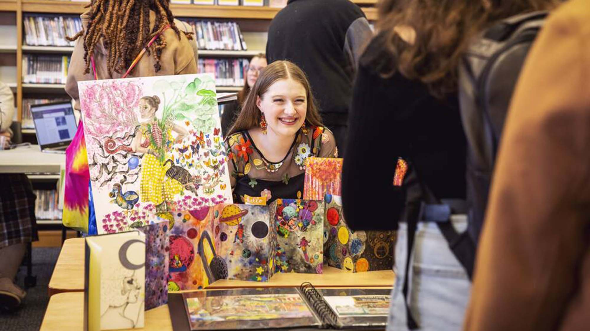a student smiling while presenting their artwork
