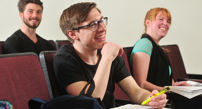 3 students smiling in a classroom setting