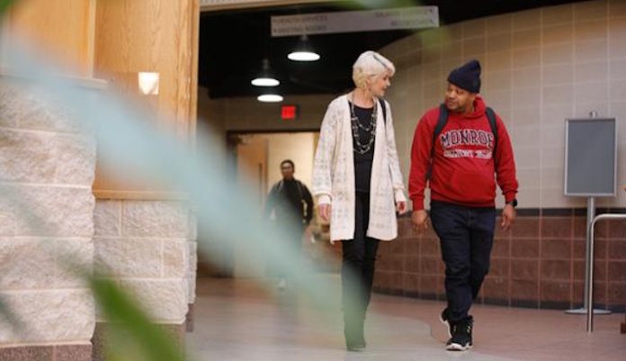 Female faculty and male student walking in hallway