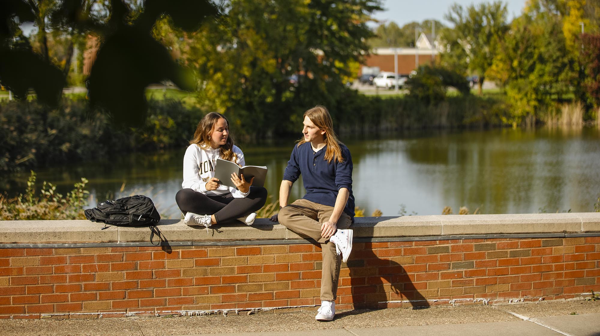 Student sitting on bench near the pond.