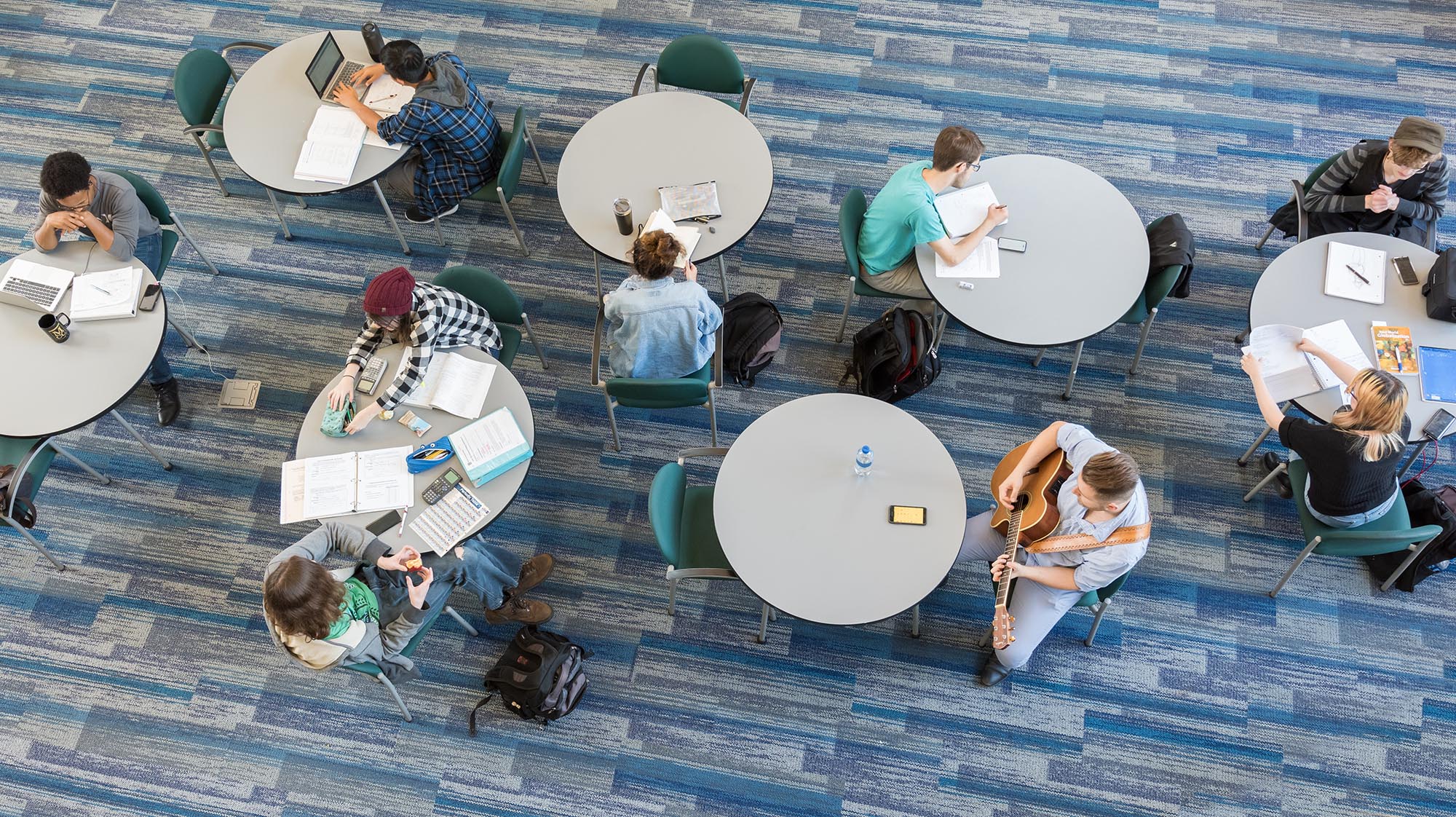 an aerial shot of students studying at circular tables