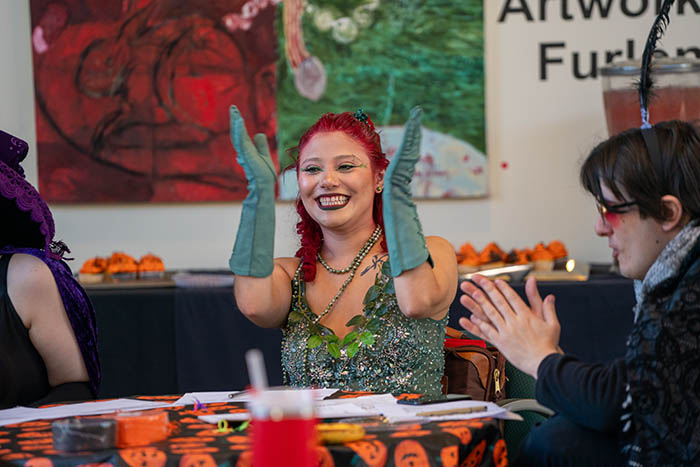 a student dressed up as poison ivy clapping their hands and smiling