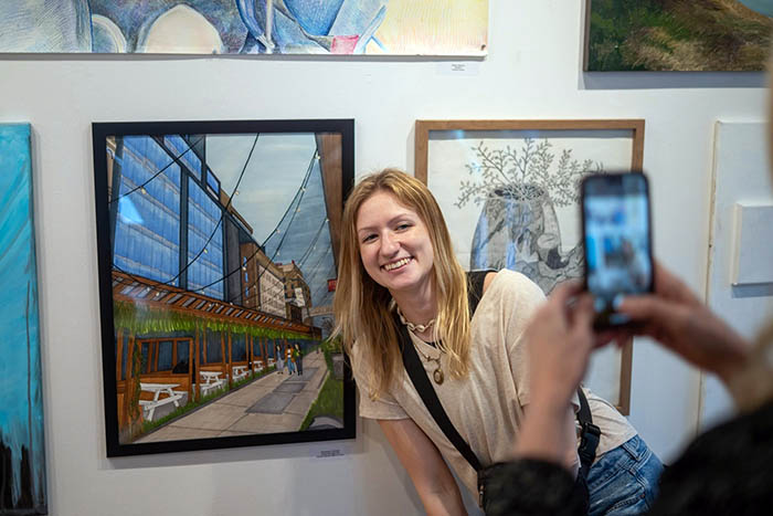 student posing with their art work