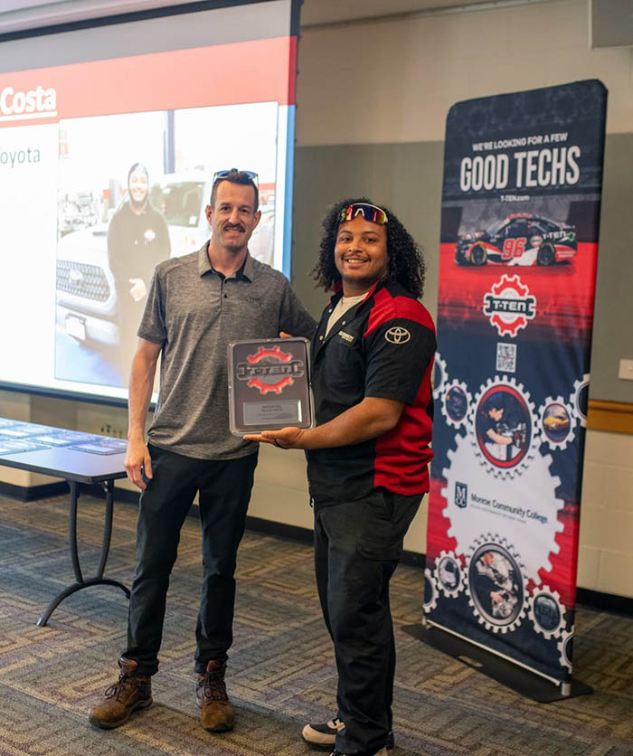 A Monroe Community College student receives an award alongside a Toyota representative at a T-TEN automotive technology event.
