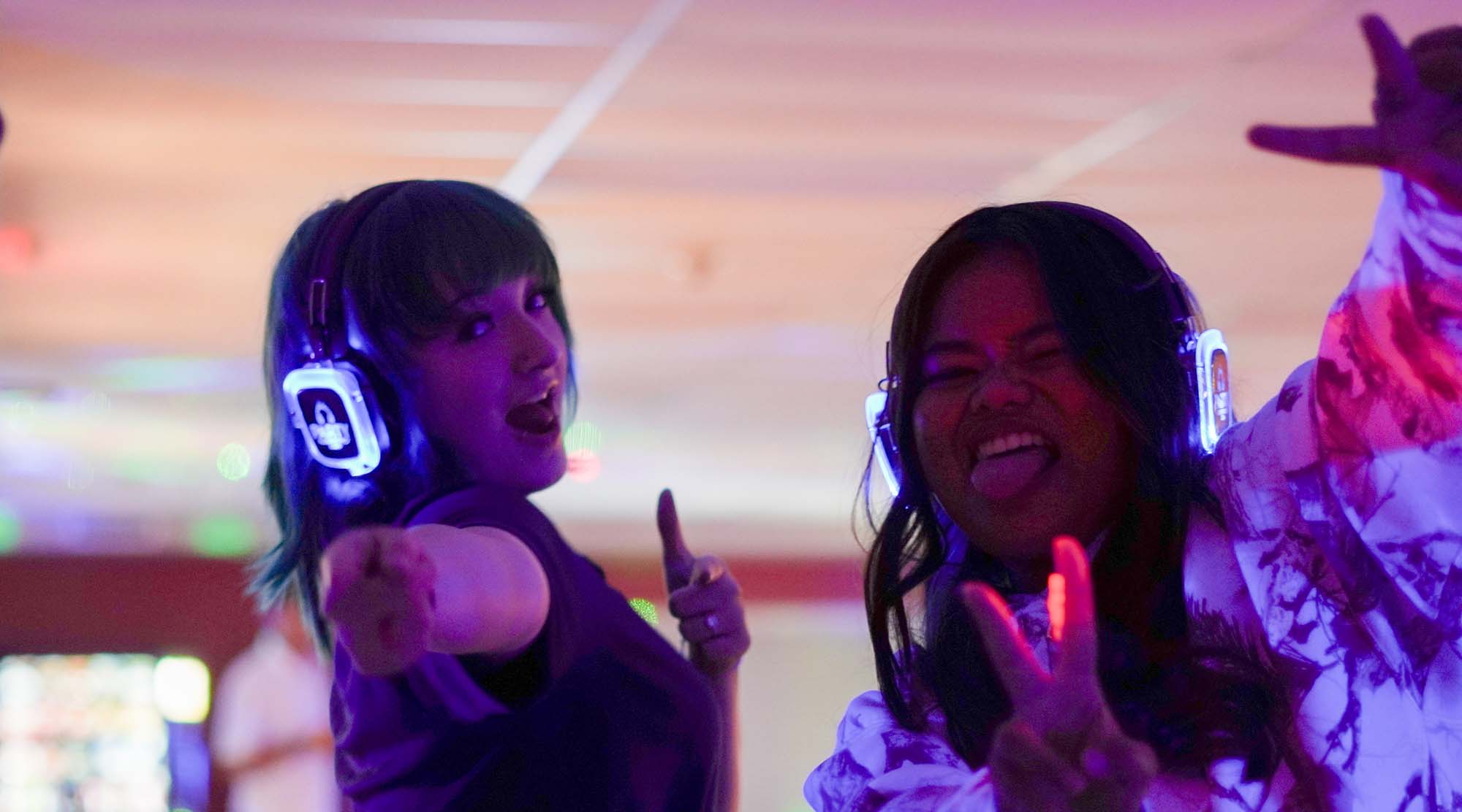 2 students wearing headphones smiling and posing