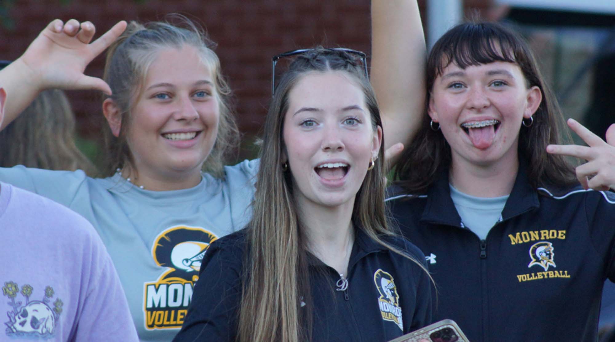 3 students smiling and posing with peace signs