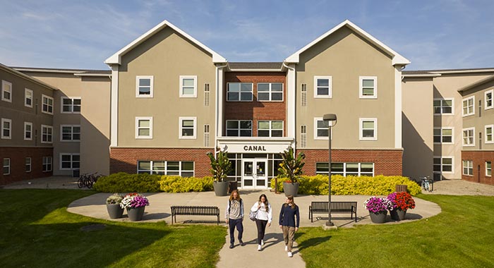 View of the Canal residence hall at Monroe Community College, surrounded by landscaped grounds and walkways.
