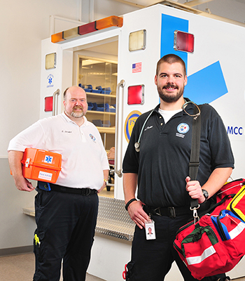 Two male MCC EMS students in front of ambulance simulator at the Public Safety Training Facility in Rochester, NY.