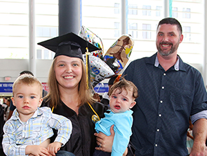 MCC Graduate at commencement with her two young children and husband.