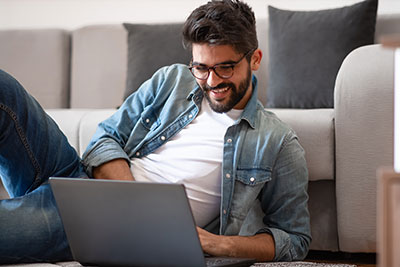 male student laying on the floor in front of a laptop