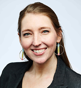 Portrait of MCC graduating student Kay Wilkoff wearing gold hoop earrings and a black blazer over a black top