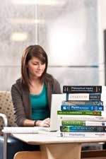 Photo of student with books at common study area