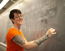 Rachel Santiago, Ed.D., 2021-22 recipient of the national League Excellence Award, writing on a blackboard