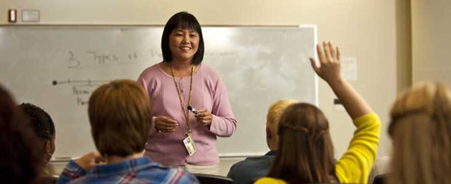 Student raising hand in classroom.