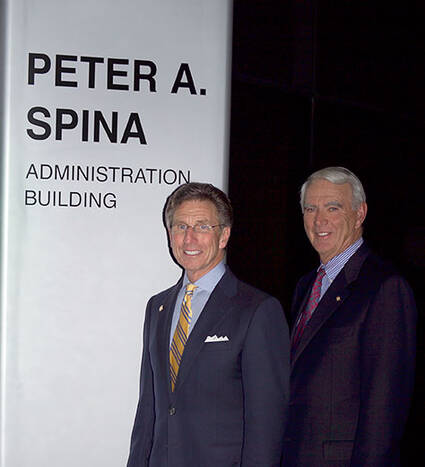 Dr. Peter Spina with Dr Thomas Flynn outside a sign naming the Peter A Spina Administration Building