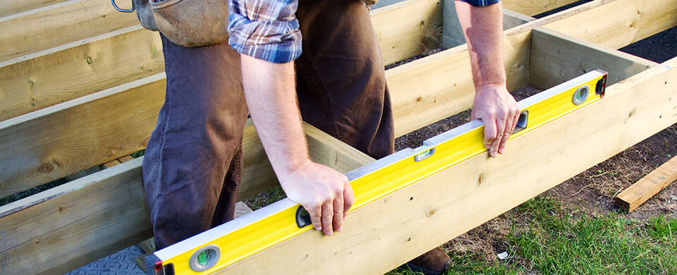 Individual using a level on a floor joist frame