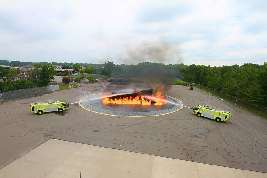 Burning fuel spill from aircraft being sprayed by two fire trucks