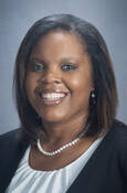 Head shot of Candice Baldwin smiling wearing a blouse with a white pearl necklace and suit jacket.