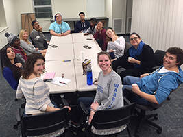 Students sitting around a table smiling