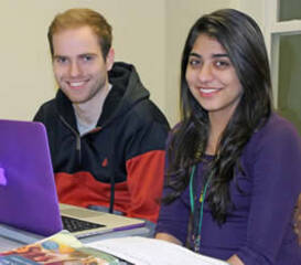 two students at a computer smiling
