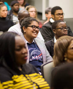 A diverse group of people seated in a lecture hall
