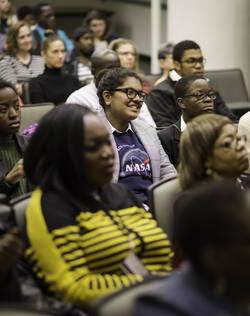 A diverse group of people seated in a lecture hall