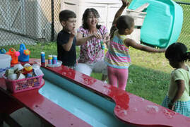 child care center kids playing at a water table outside