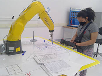 High school student operating FANUC robot in Forward Center summer robotics program