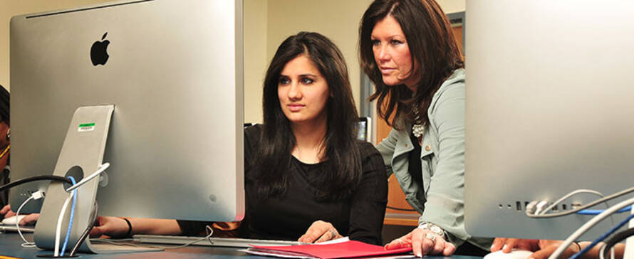 student at a computer being helped by a support person