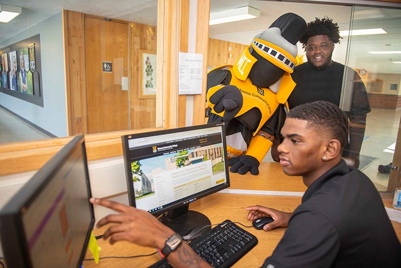 Peer Navigator helping MCC Mascot and student at Trib411 window